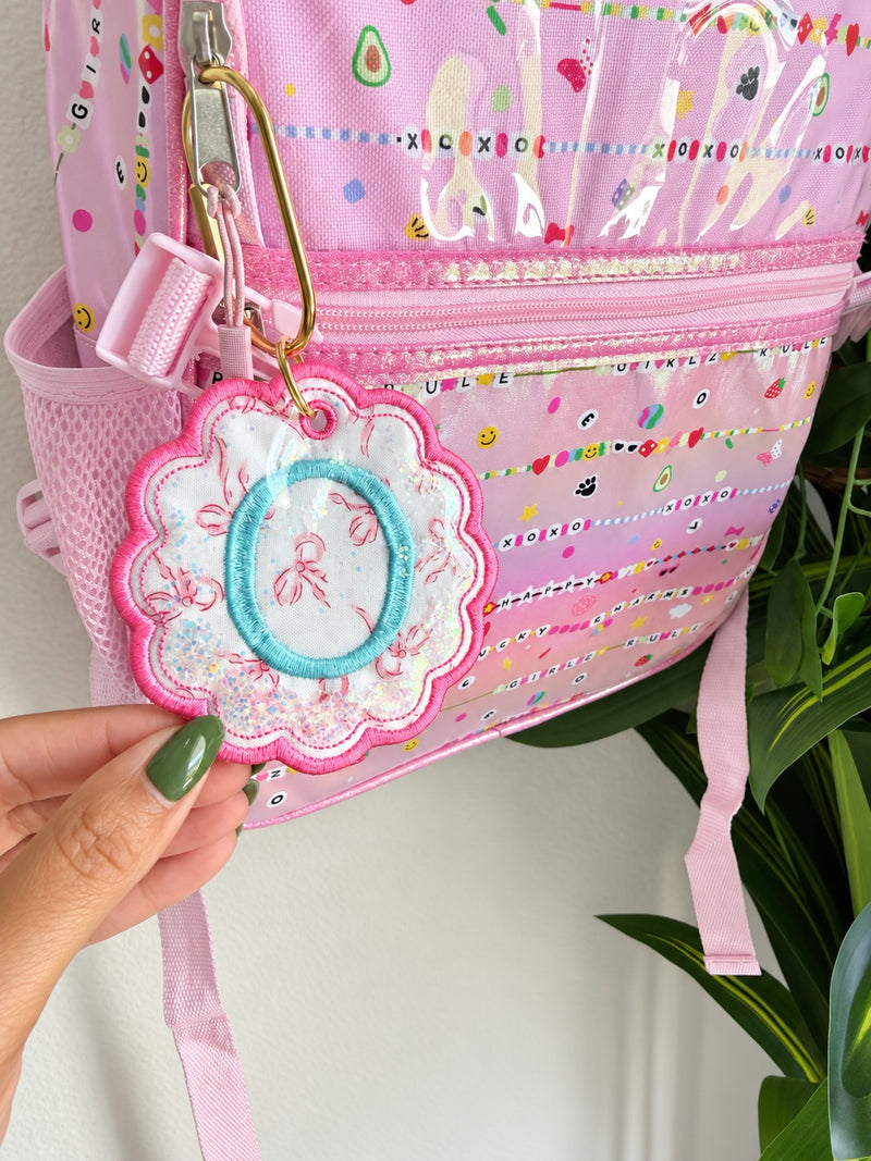 Sample: close-up of the initial O bag tag, light blue letter on bow fabric with a pink scalloped border