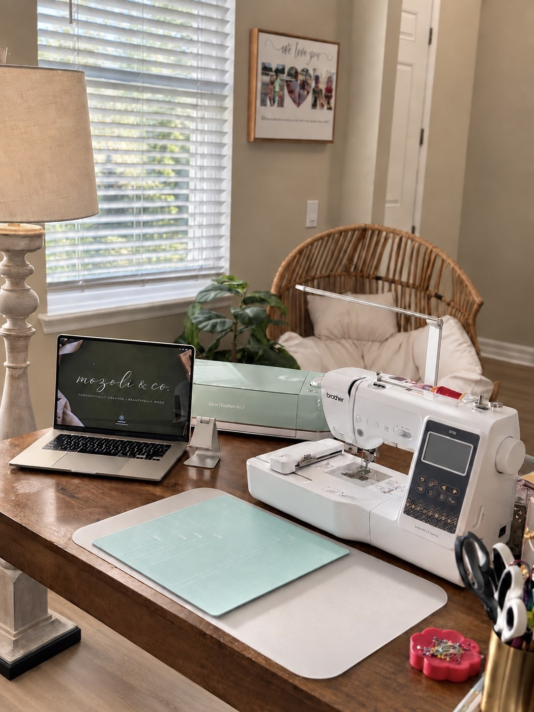 The Mozoli & Co. studio: embroidery machine, cutting machine and laptop on a wooden worktable